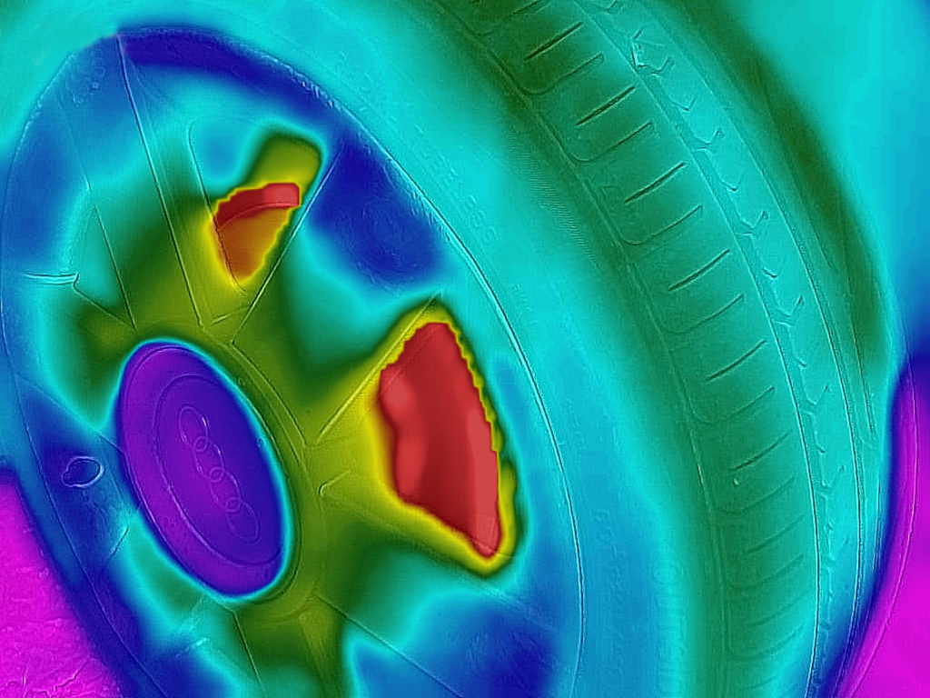 Infrared image taken with smartphone of wheel showing heat (red) from brake discs.